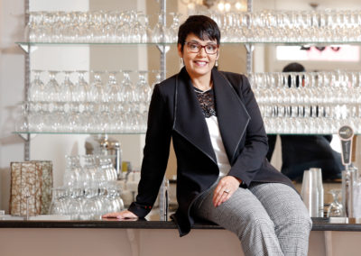 Professional portrait of a woman in front of drinking glasses